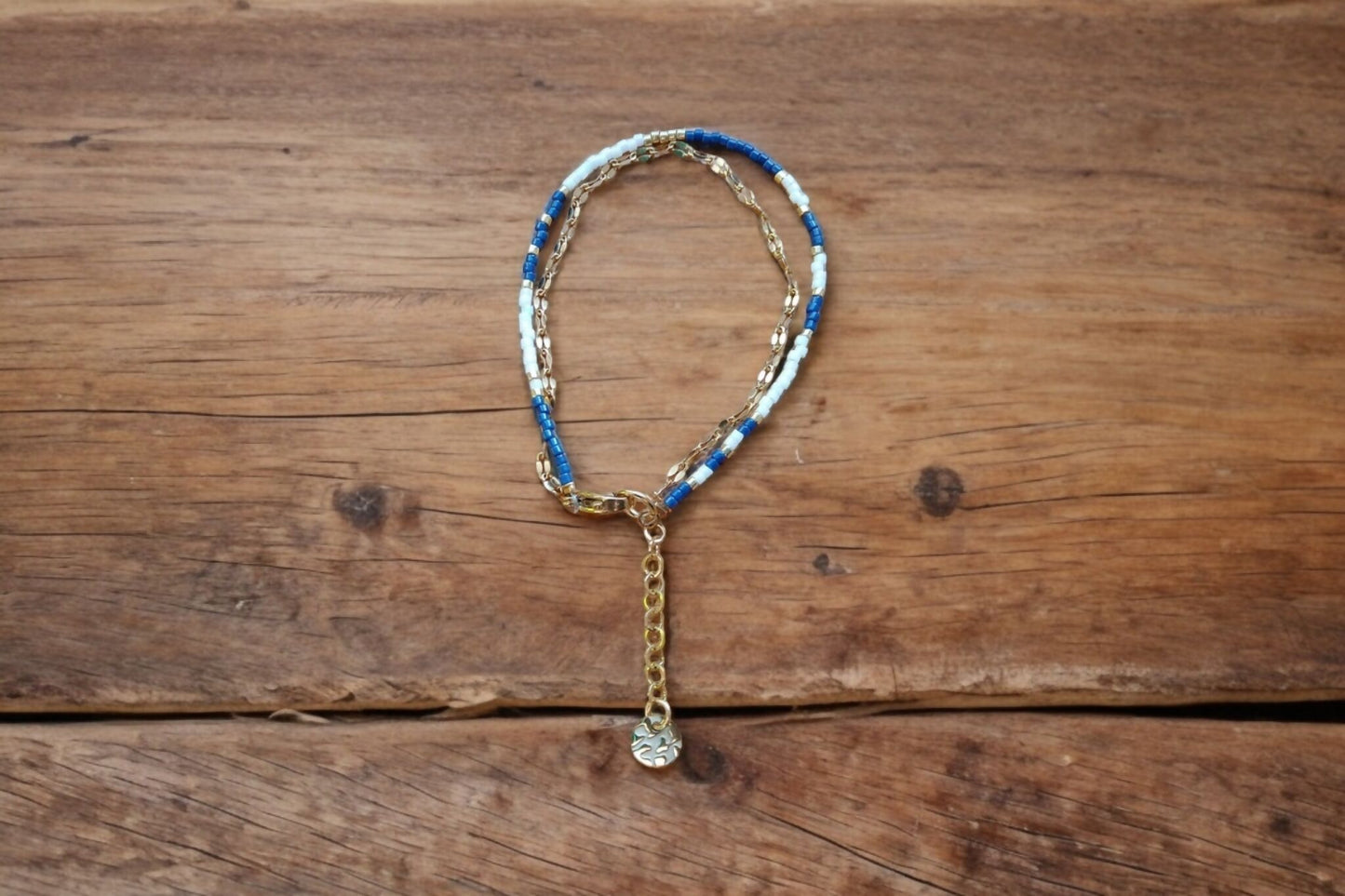 Bracelet de perles bleu marine et blanc et chaîne dorée.