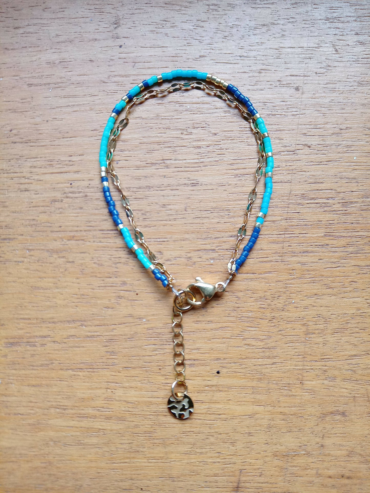 Bracelet de perles trois bleus et chaîne dorée.