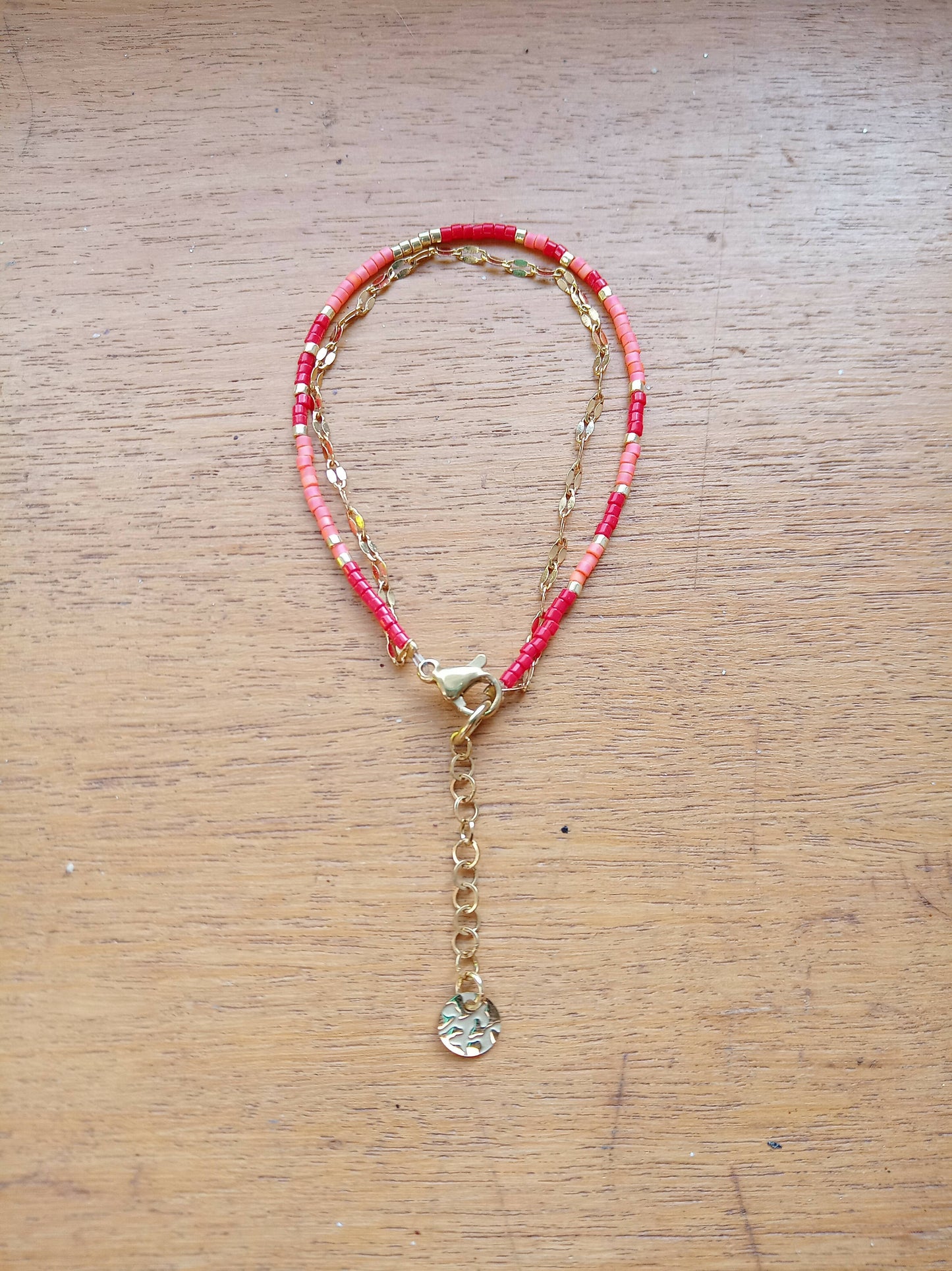 Bracelet de perles rouge et corail et chaîne dorée.