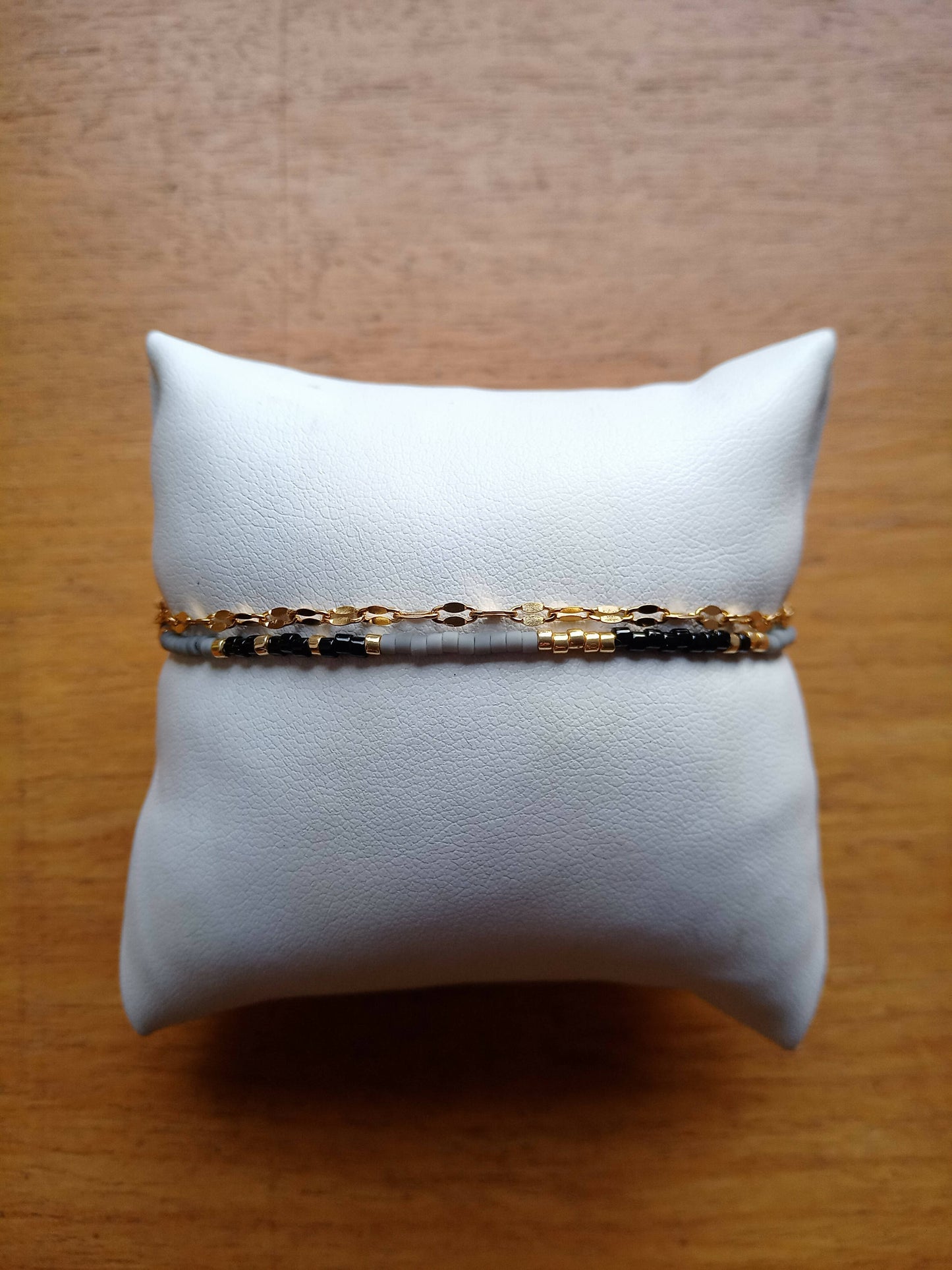Bracelet de perles noir et gris et chaîne dorée.