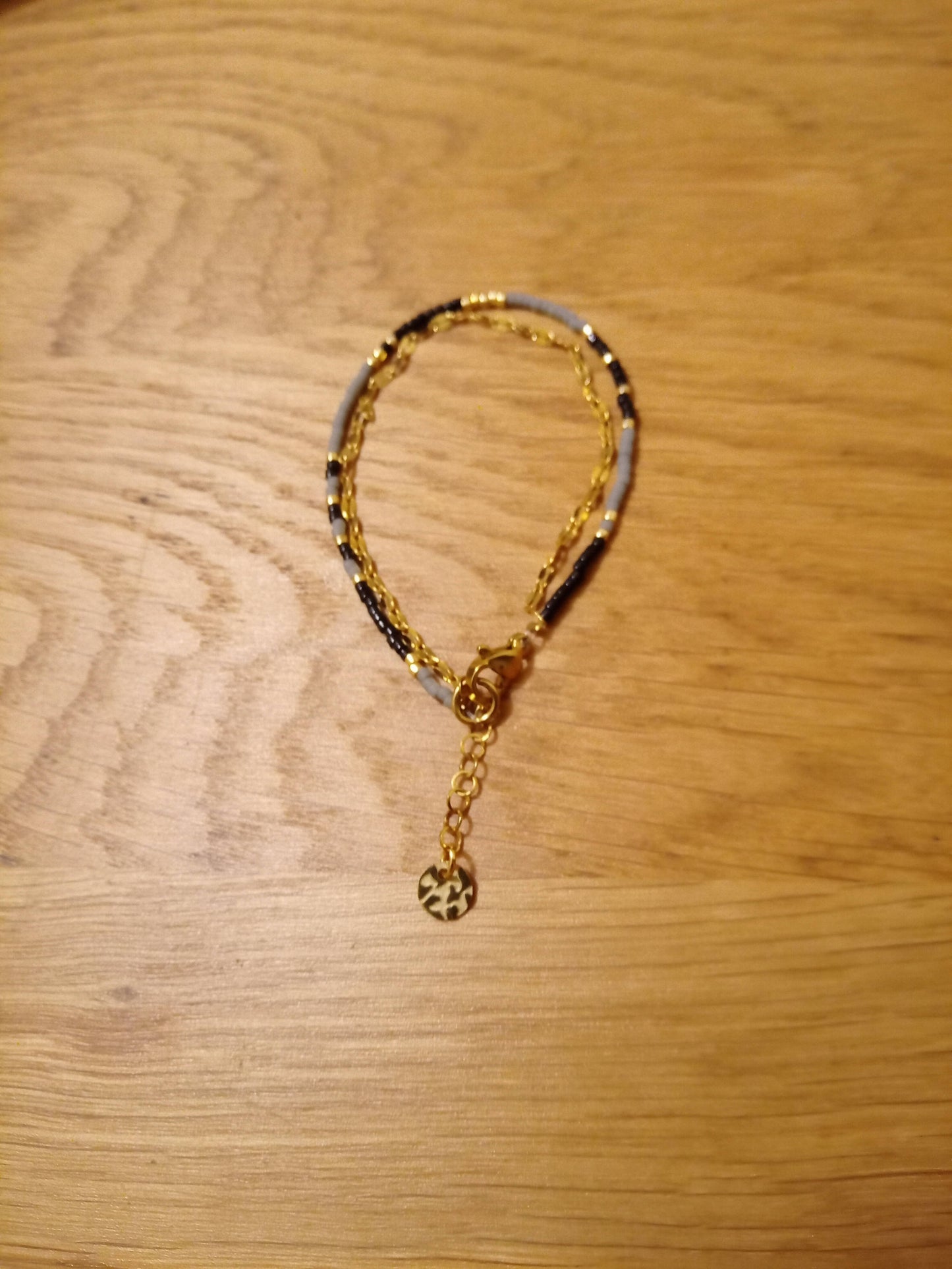 Bracelet de perles noir et gris et chaîne dorée.